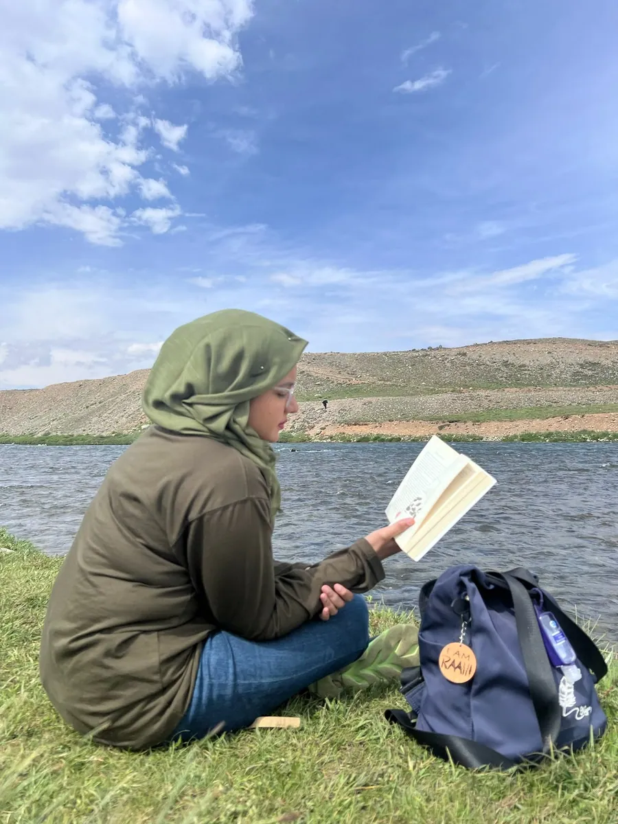 A traveller reading beside a lake