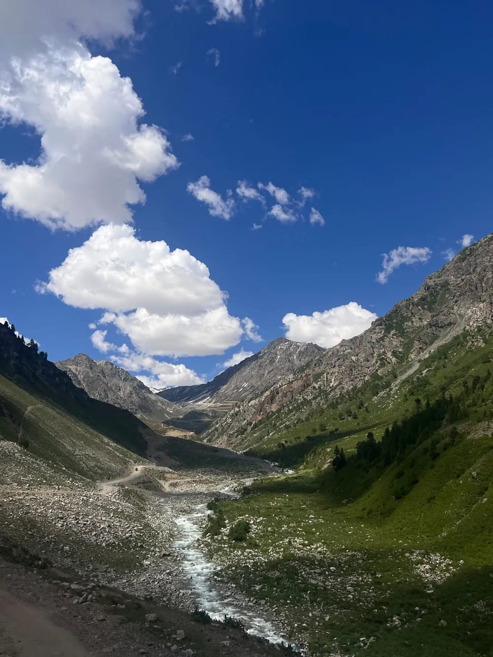 A Green Valley And Stream Between High Mountains