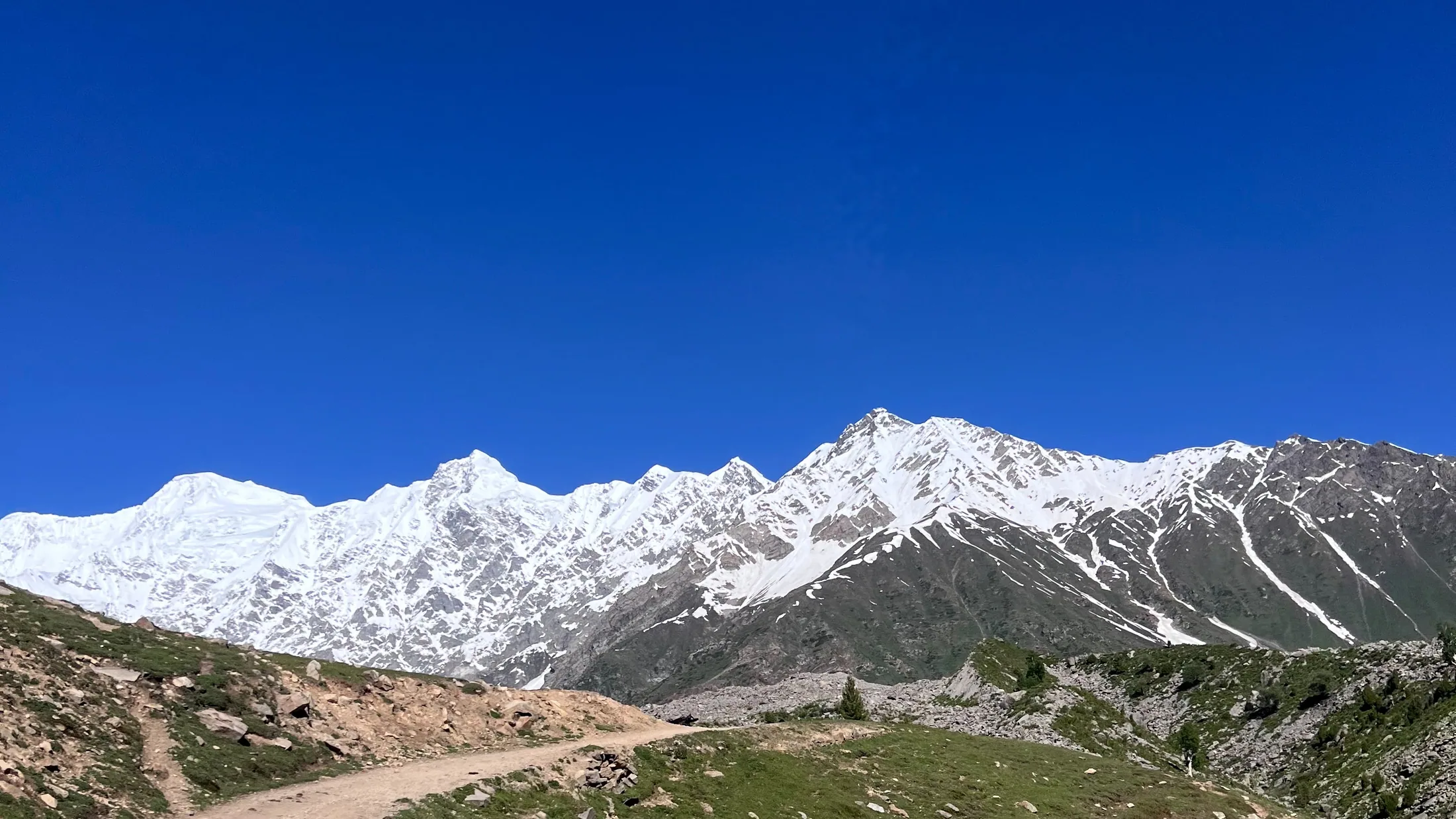 A track leading towards a snow-covered mountain range in northern Pakistan