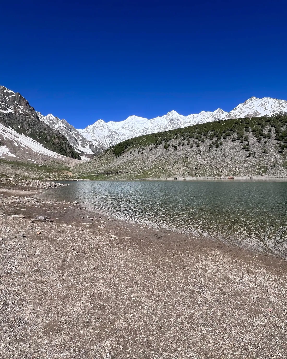 A still alpine lake below snow-covered peaks