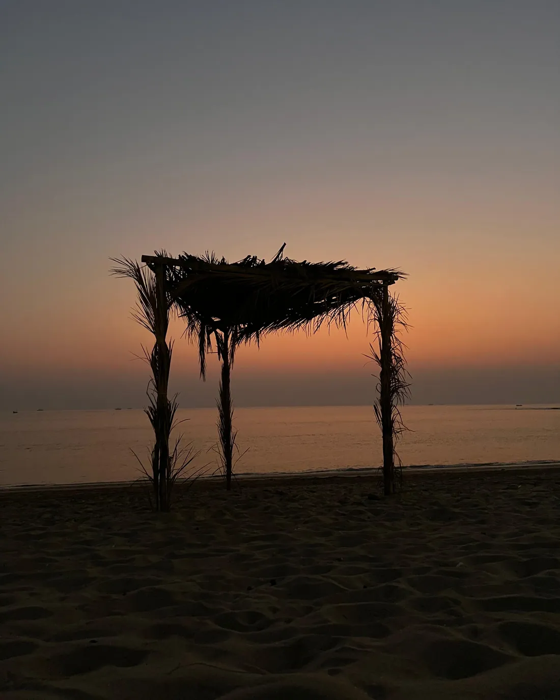A driftwood shelter on the beach at sunset on the Sindh coast